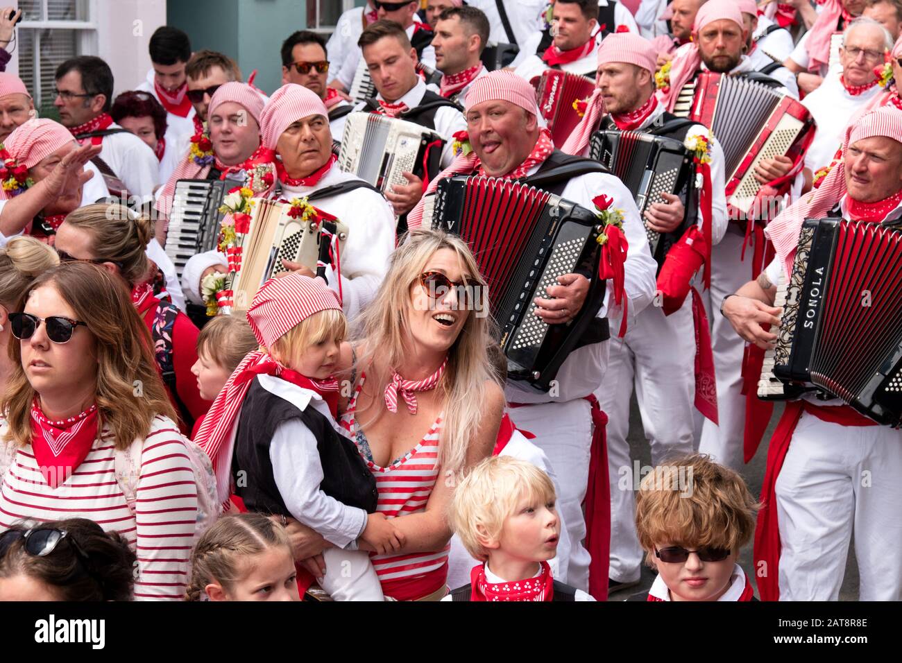 Akkordeonspieler, der Akkordeonspieler spielt und dem roten Band Obby Oss Procession, Padstow, Cornwall, Großbritannien folgt Stockfoto