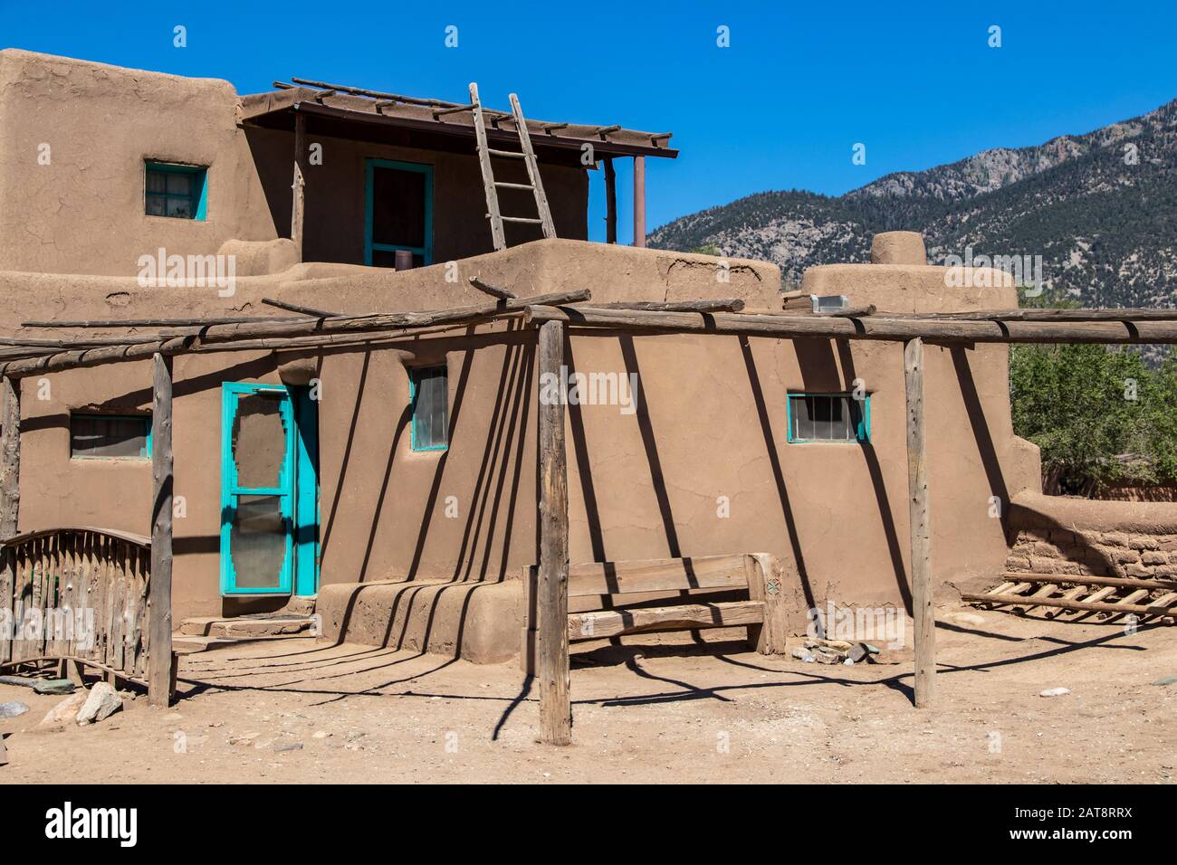 Mehrstöckige Gebäude aus Adobe Mud in Pueblo-Dorf, die seit mehr als 1000 Jahren ununterbrochen bewohnt werden, mit Bergen in New Mexico in der Ferne Stockfoto