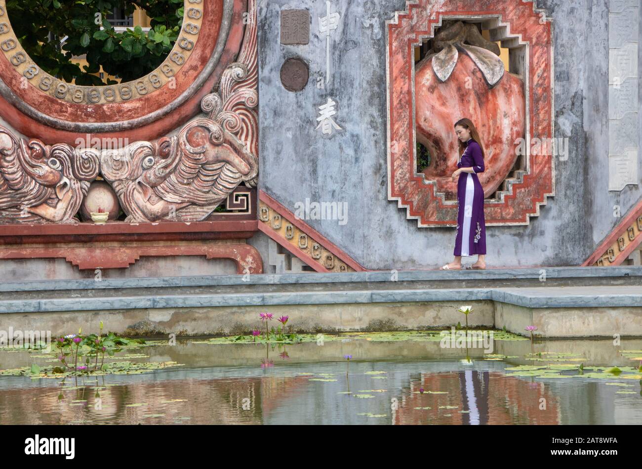 In Hoi An, Vietnam, am august 2019 - Mädchen, das im Brunnen des Tam Quan Tores oder Dreieingangstors reflektiert wird, führt zum alten Tempelkomplex bu Stockfoto