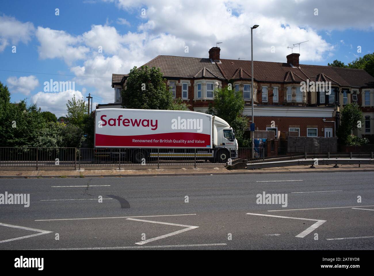 Safeway Supermarkt-Lkw mit dem Logo, das für britische Qualität und Wert bekannt ist, fahren auf einer Straße mit Häusern dahinter. Stockfoto