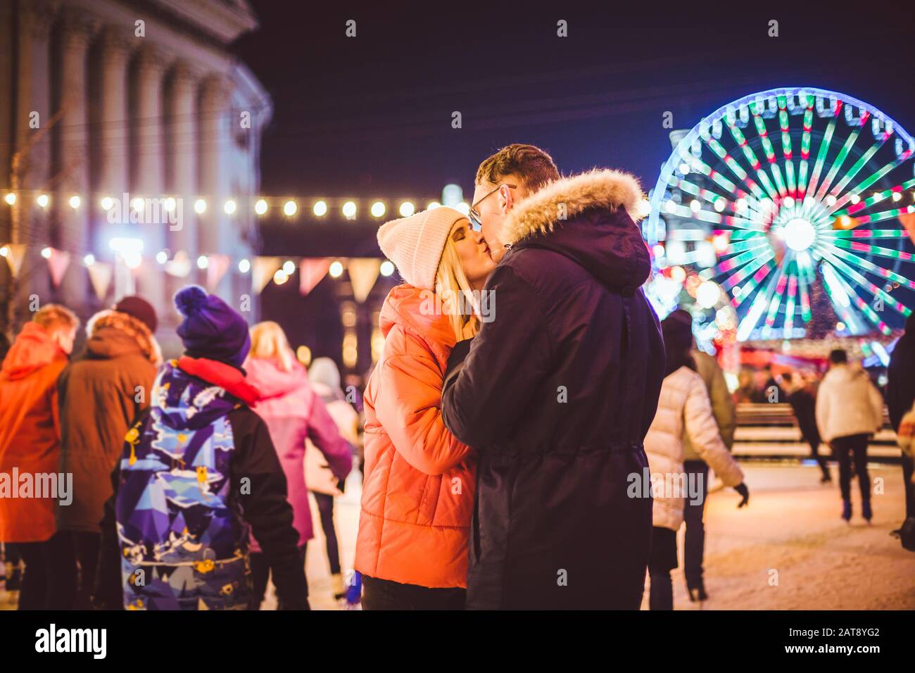 Schönes Paar Eislaufen Im Stadtzentrum. Junge Paare, die auf einer öffentlichen Eislaufbahn im Freien Schlittschuhlaufen. Thema Eislaufbahn und liebevolles Paar Stockfoto