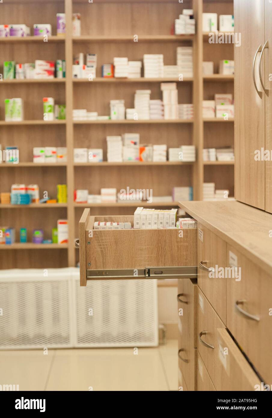 Offene Schachtel mit Medikamenten in einer Apotheke im Hintergrund von Regalen mit Tablettenpackungen und Kapseln am Tag Stockfoto
