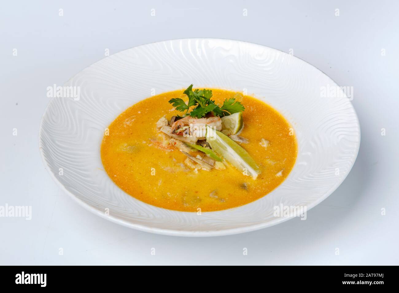 Käsesuppe mit Garnelen. Gelbe Suppe ist mit Zitrone und Petersilie verziert. Auf weißem Hintergrund Stockfoto