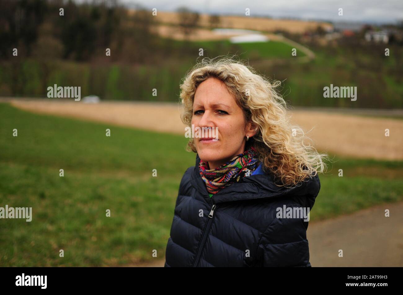 Blonde junge Frau mit Locken im starken Wind in der Natur Stockfoto