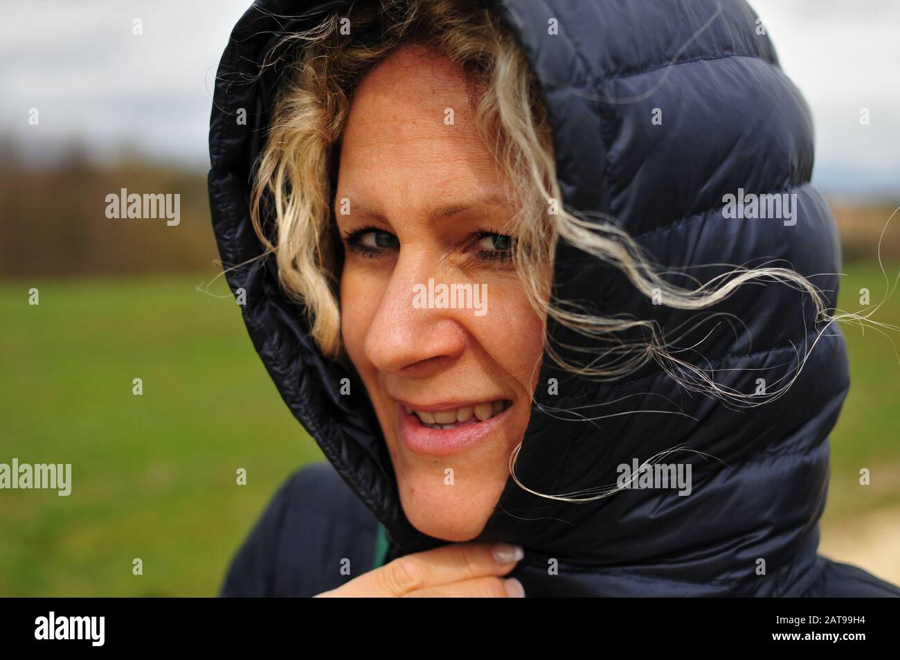 Blonde junge Frau mit Locken im starken Wind in der Natur Stockfoto