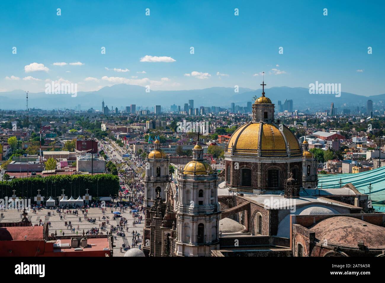 Mexiko-Stadt, Mexiko, die Basilika Unserer Lieben Frau von Guadalupe mit der Skyline von Mexiko-Stadt im Hintergrund. Stockfoto