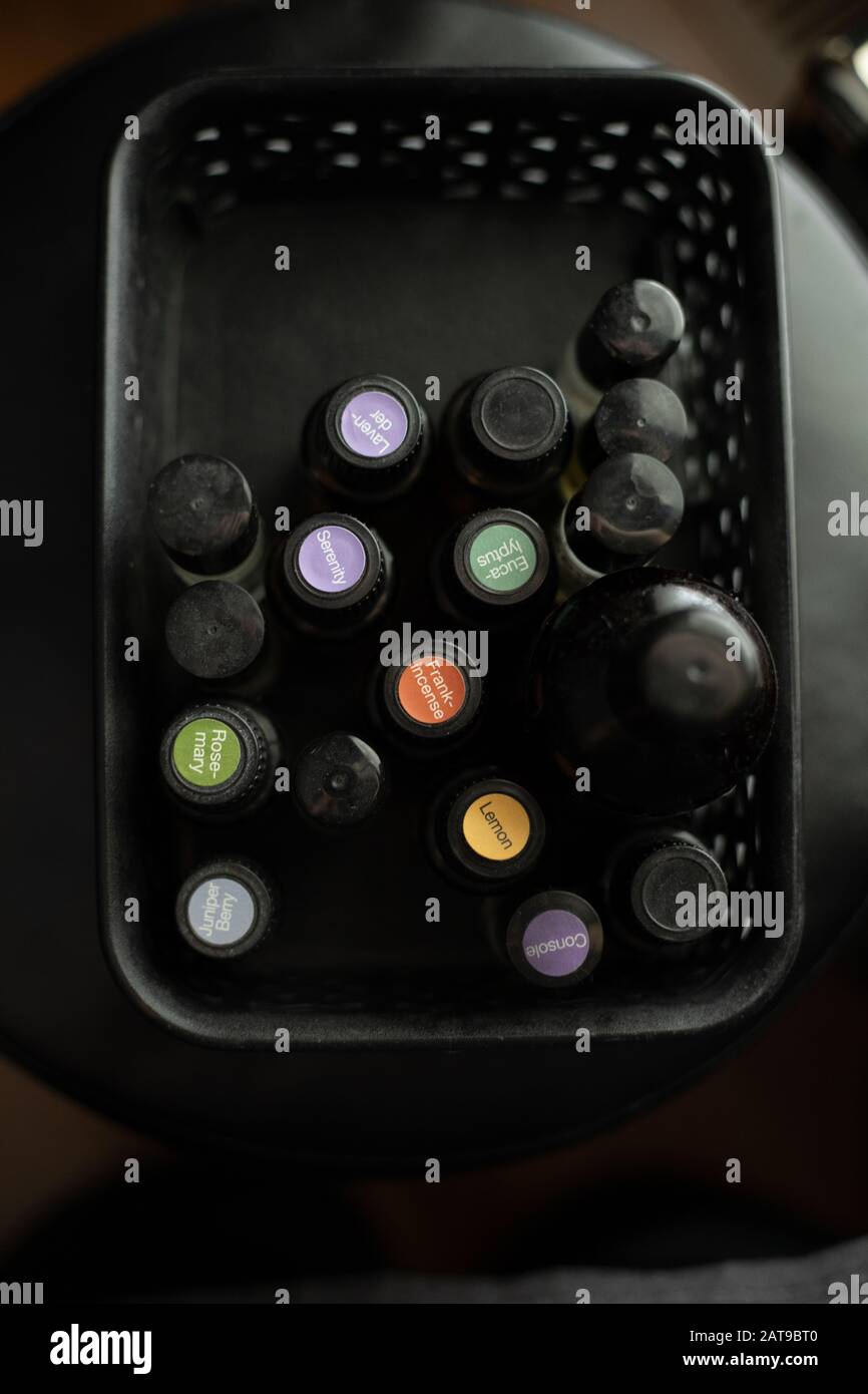 Deckel von Glasflaschen mit ätherischen Ölen in einem schwarzen Behälter nach unten füllen Stockfoto