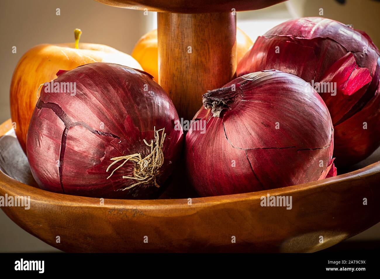 Rote Zwiebeln in Holzschale auf sonniger Fensterbank Stockfoto