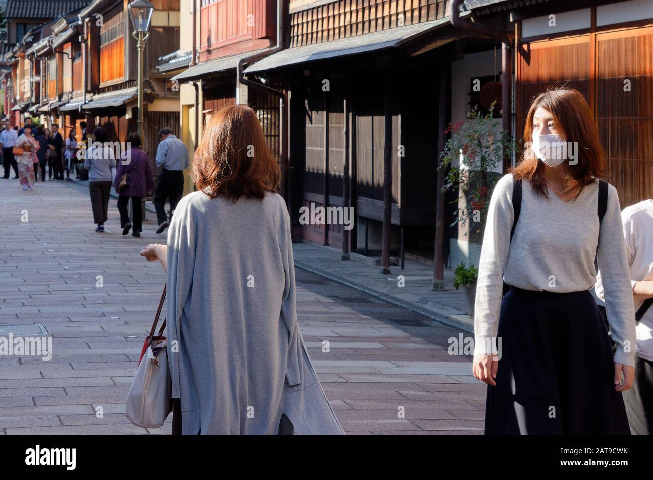 Zwei junge Frauen, eine mit Maske, im Higashi-Chaya-Distrikt ('Eastern Teahouse-Distrikt') von Kanazawa. Stockfoto