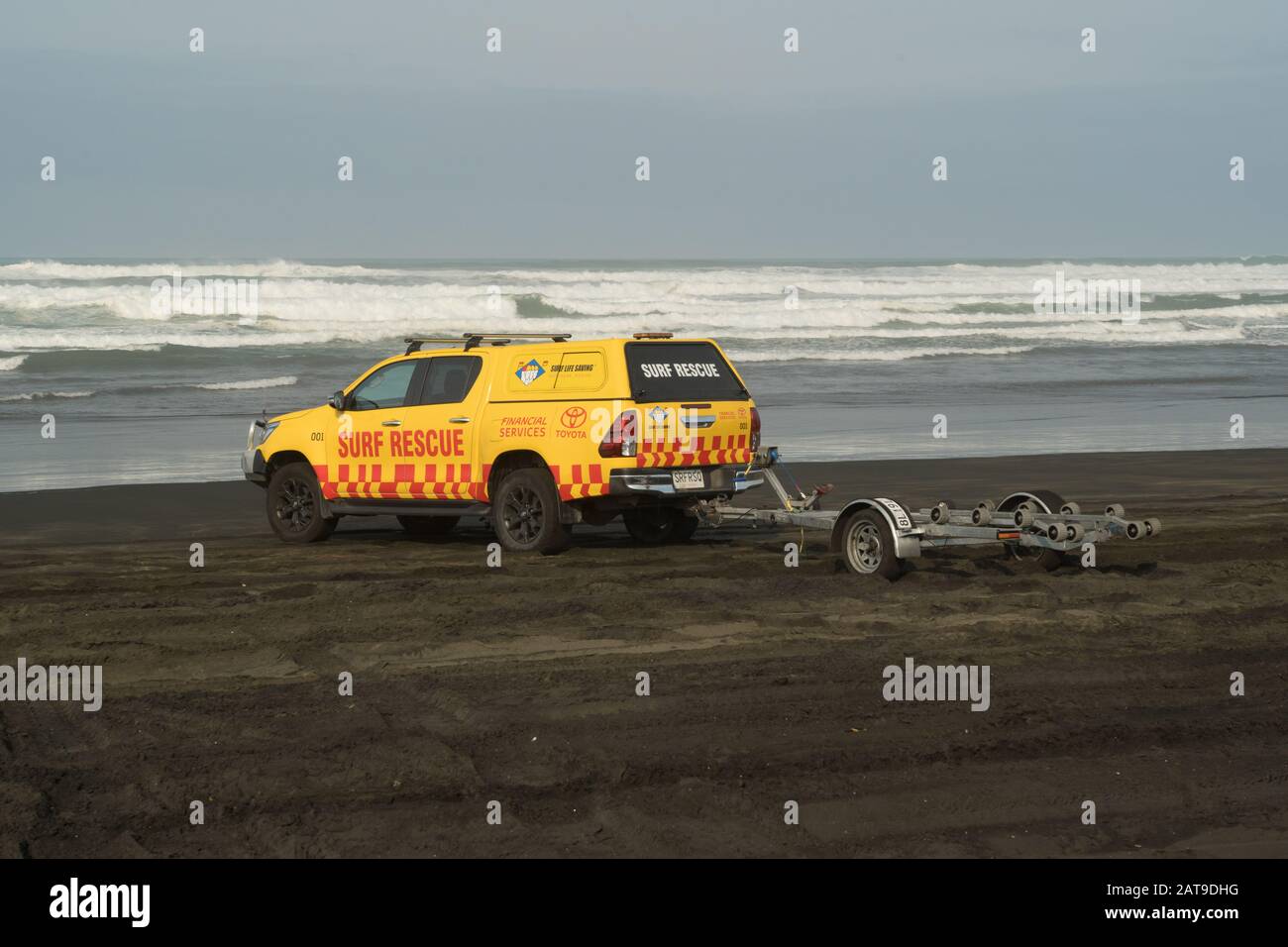 Surf Rescue 4WD Truck am schwarzen Sandstrand mit Jet-Skiboot Trailer Seewellen Himmel Hintergrund muriwai Strand, Auckland, Neuseeland Stockfoto