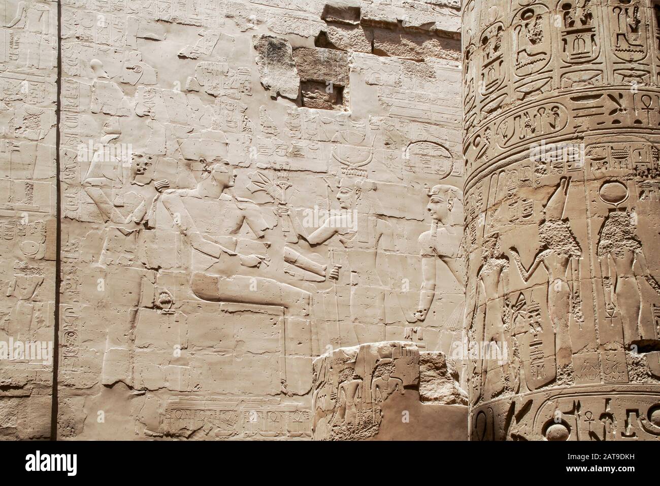 Luxor, Karnak, Ägypten, Afrika. Tempel von Karnak. Detail der Reliefschnitzereien eines Mannes und einer Frau an der Wand und der Hieroglyphen an der Säule. Stockfoto