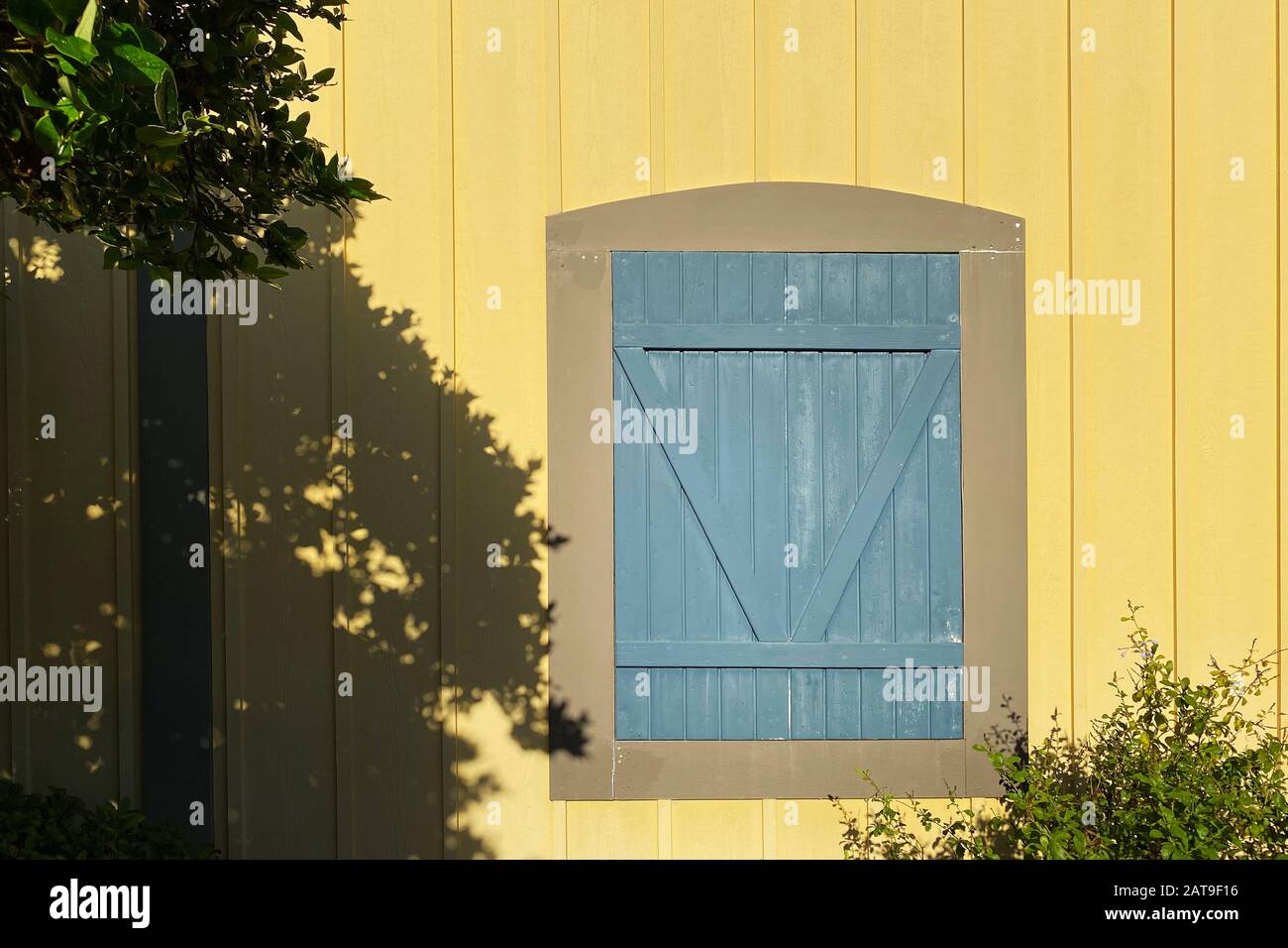 Ein gelbes Bauernhaus mit blauer Scheunentür mit tiefen Schatten Stockfoto