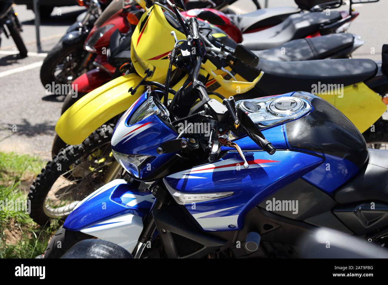 Motorrad: Bunte Fahrräder in Folge, außerhalb der Stadt an einem warmen hellen Tag geparkt. Landschaftsbild. Stockfoto