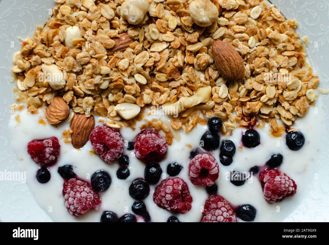 Gesundes Frühstück, Granola mit Joghurt und gefrorenen Himbeeren und Blaubeeren, in der Nähe Stockfoto