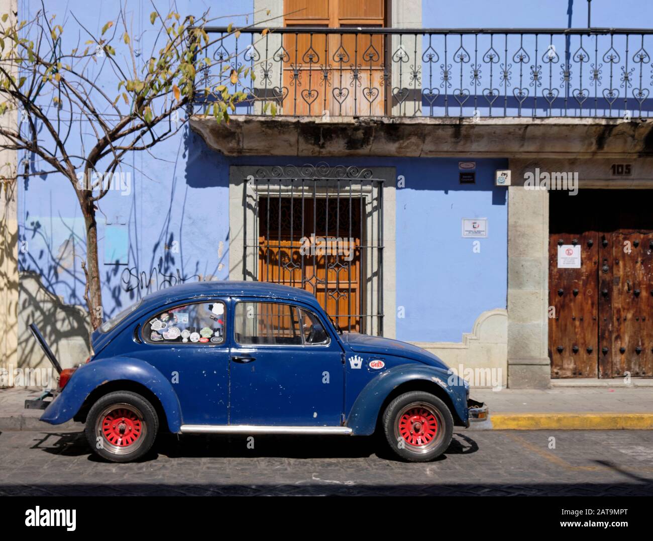 Blauer klassischer VW-Käferwagen, der an der Seite der Stadtstraße vor einem blauen Kolonialgebäude in Oaxaca Mexiko geparkt ist Stockfoto