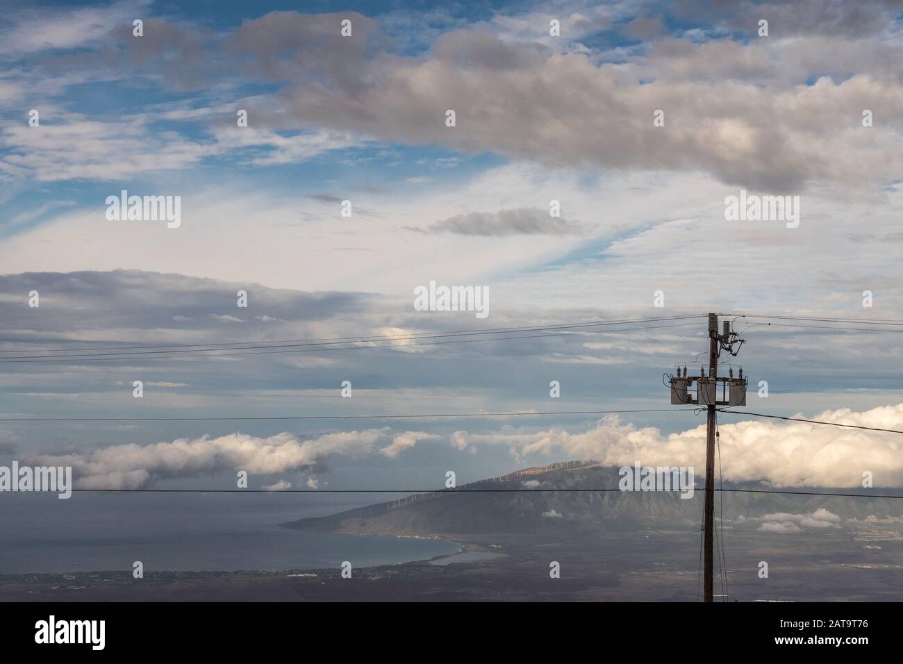 Kahului, Maui, Hawaii, USA. - 13. Januar 2020: Verschiedene Wolkenschichten in blauem Himmel über Land und Ozean mit Bergen am Horizont. Elektrischer Pol Stockfoto