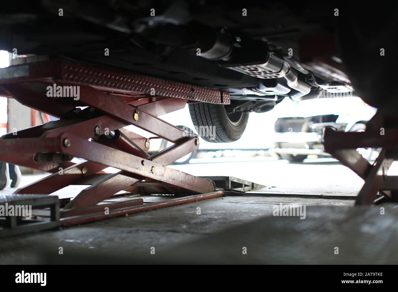 Das Auto wurde auf einem Aufzug zur Reparatur in einem Auto gehoben Stockfoto