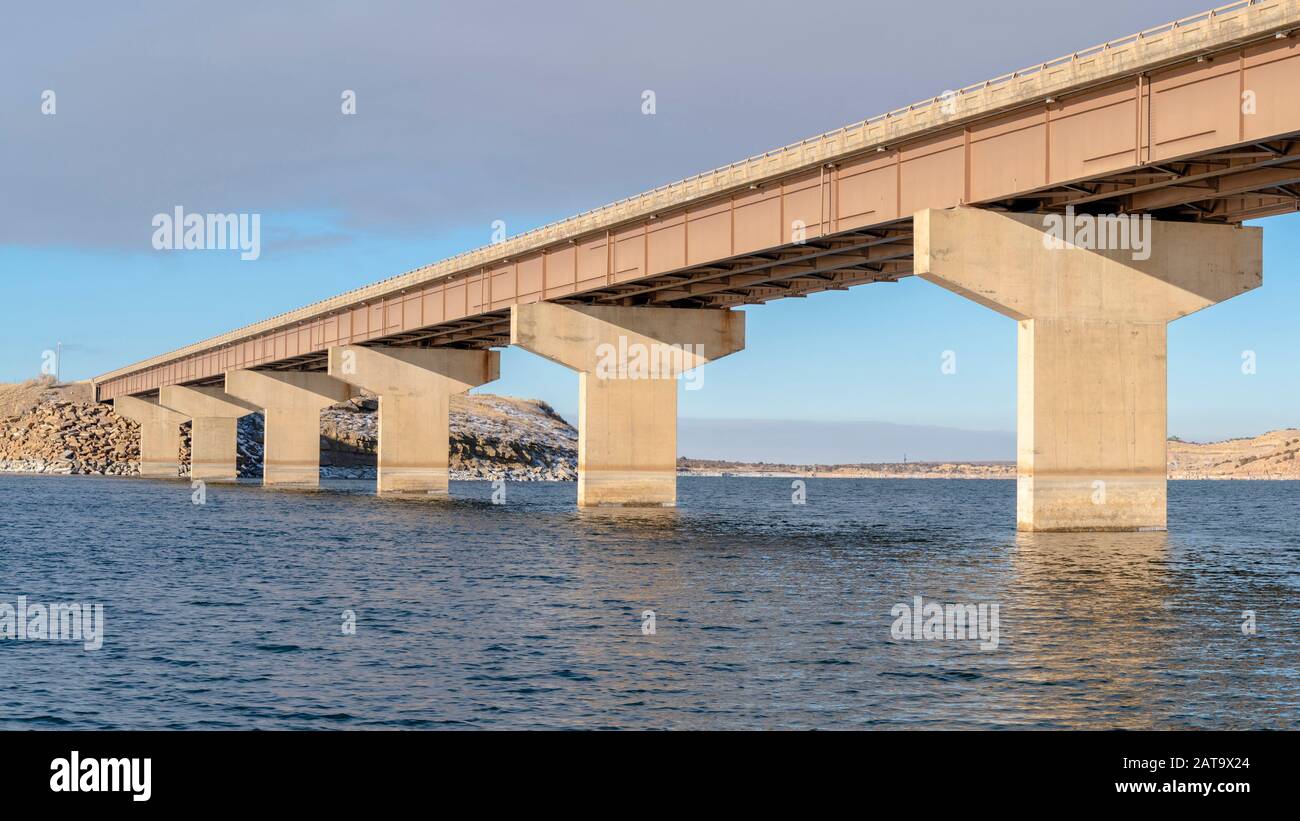 Panorama Stringer Brücke über einen See mit Blick auf verschneite Gelände und wolkenbedeckten Himmel Stockfoto