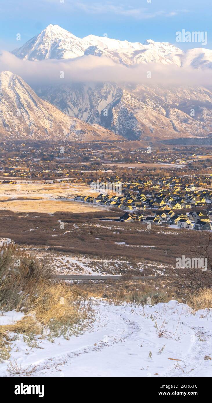 Foto Vertikal schneebedeckter Berg Timpanogos, der über Nachbarhäusern im Tal thront Stockfoto