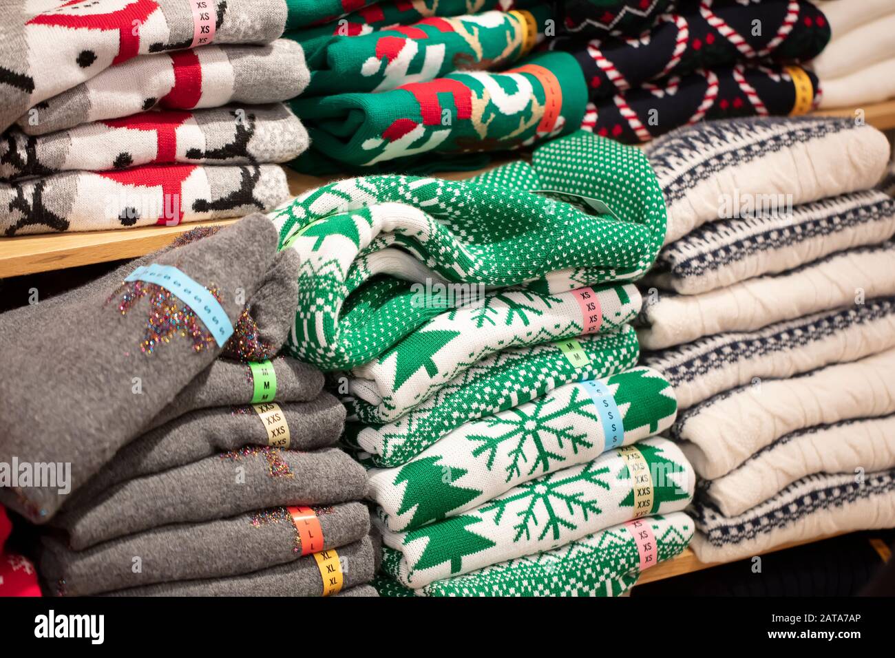Pullover mit Weihnachtsornamenten im Laden.Stapel aus gefalteten Strickwaren Stockfoto