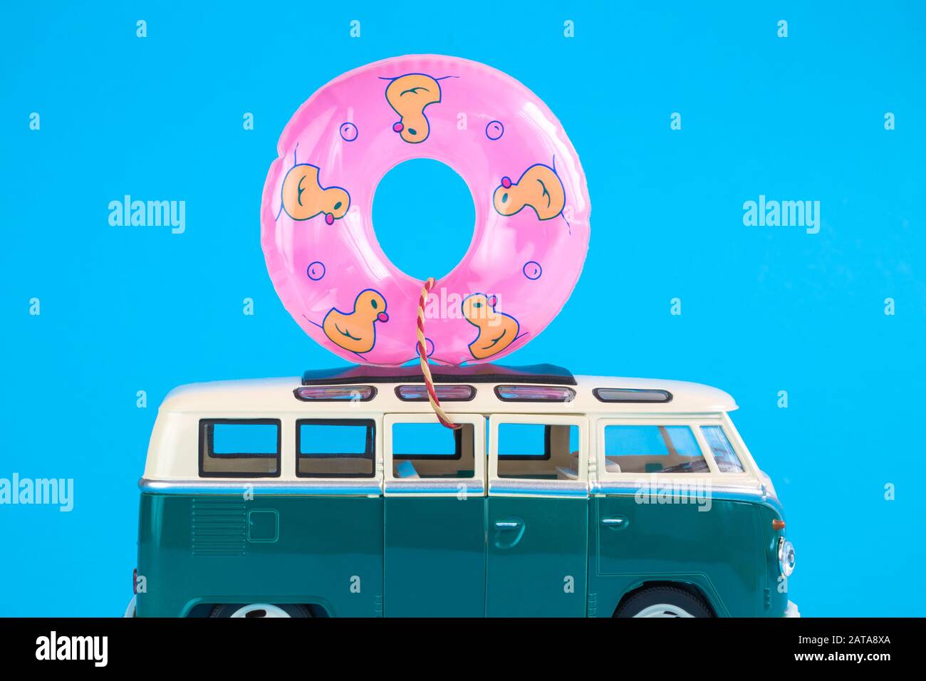 Retro-van-Spielzeug mit aufblasbarem Pool schwimmt vor blauem Hintergrund minimales kreatives Reise- und Sommerferienkonzept. Stockfoto