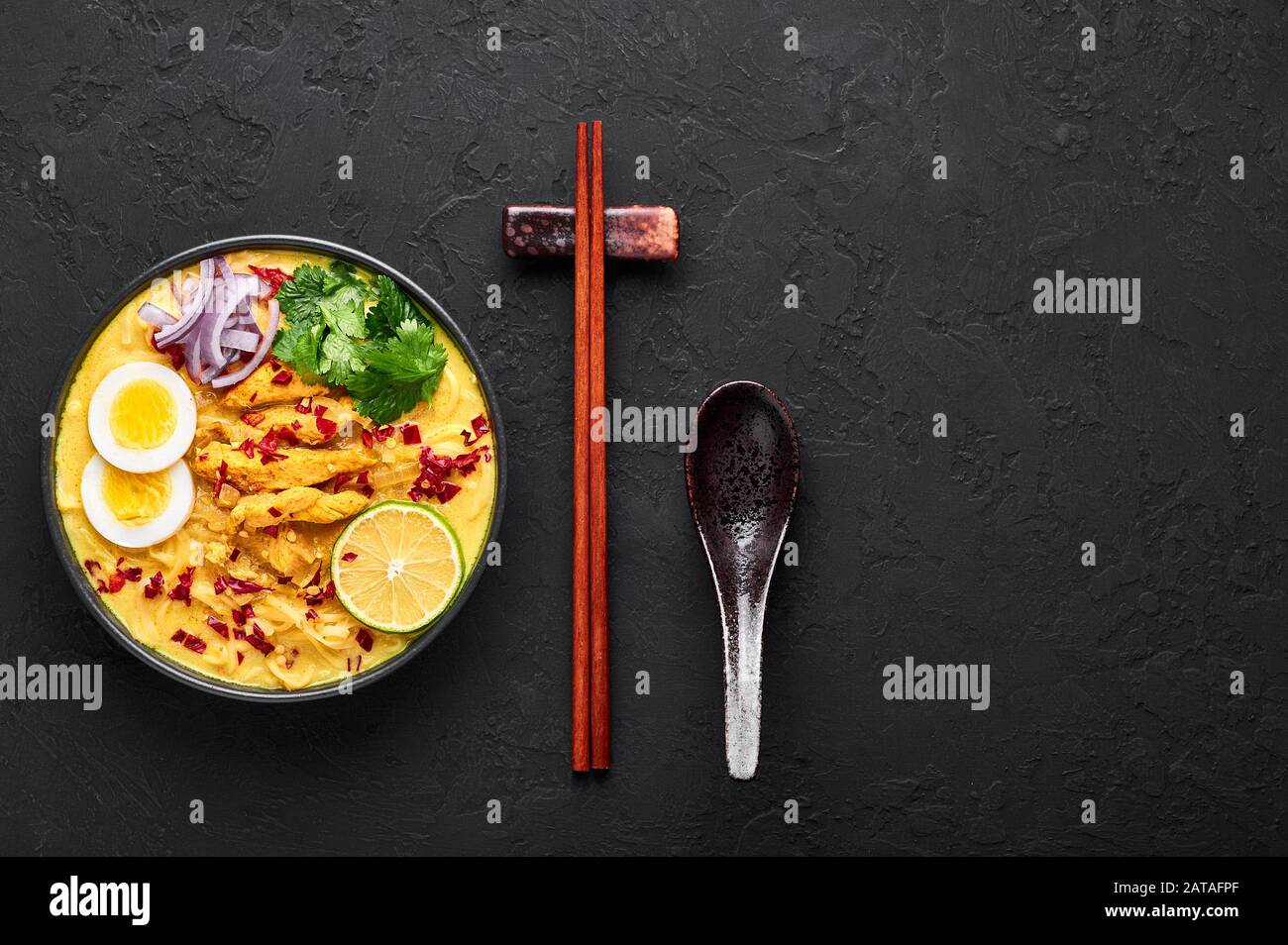 Ohn No Khao Swe in schwarzer Schüssel mit dunklem Schieferhintergrund. Oh No Khao Suey ist Coconut Milk Noodle Suppe der küche myanmars mit Hühnerfleisch und Eiern. Bur Stockfoto