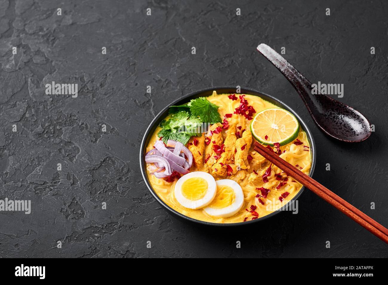 Ohn No Khao Swe in schwarzer Schüssel mit dunklem Schieferhintergrund. Oh No Khao Suey ist Coconut Milk Noodle Suppe der küche myanmars mit Hühnerfleisch und Eiern. Bur Stockfoto