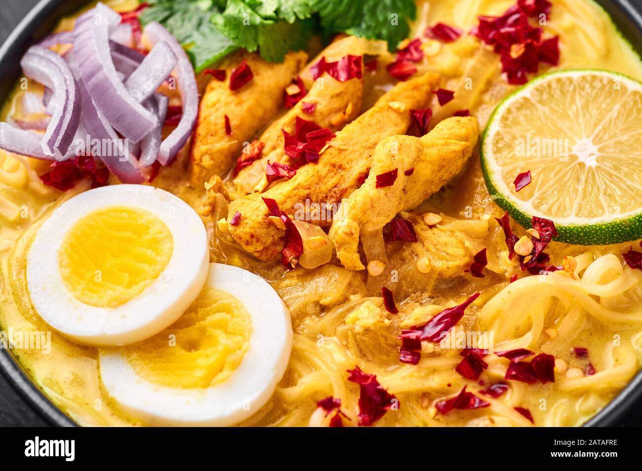 Ohn No Khao Swe in schwarzer Schüssel mit dunklem Schieferhintergrund. Oh No Khao Suey ist Coconut Milk Noodle Suppe der küche myanmars mit Hühnerfleisch und Eiern. Bur Stockfoto