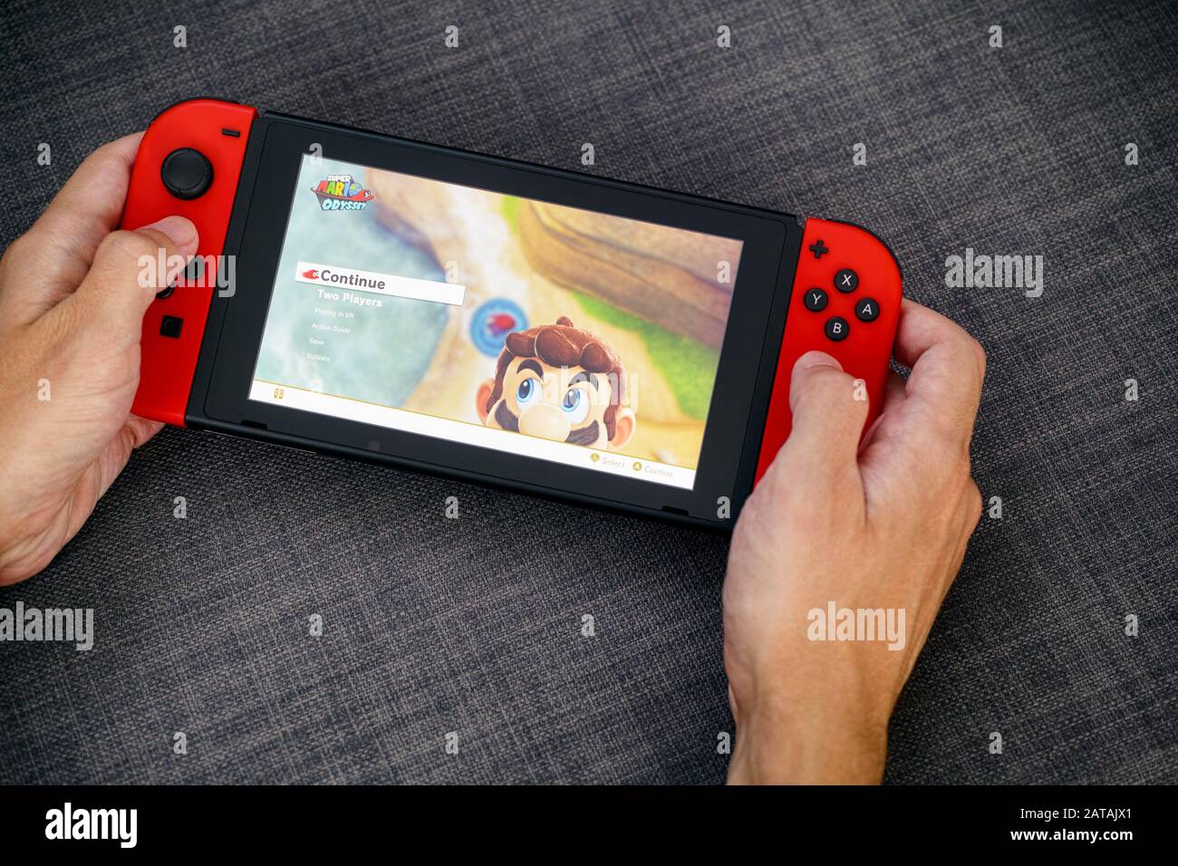 Tambov, Russische Föderation - 22. Juni 2019 Person übergibt sich das Spielen von Super Mario Maker 2 Videospiel auf der Videospielkonsole von Nintendo Switch. Grauer Hintergrund. Stockfoto