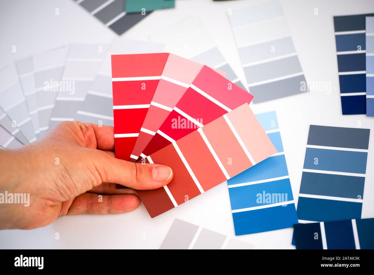 Frau Hand wählt rote Malfarben in Probenpaletten. Nahaufnahme. Stockfoto Frau Hand wählt rote Malfarben in Probenpaletten. Nahaufnahme. Stockfoto