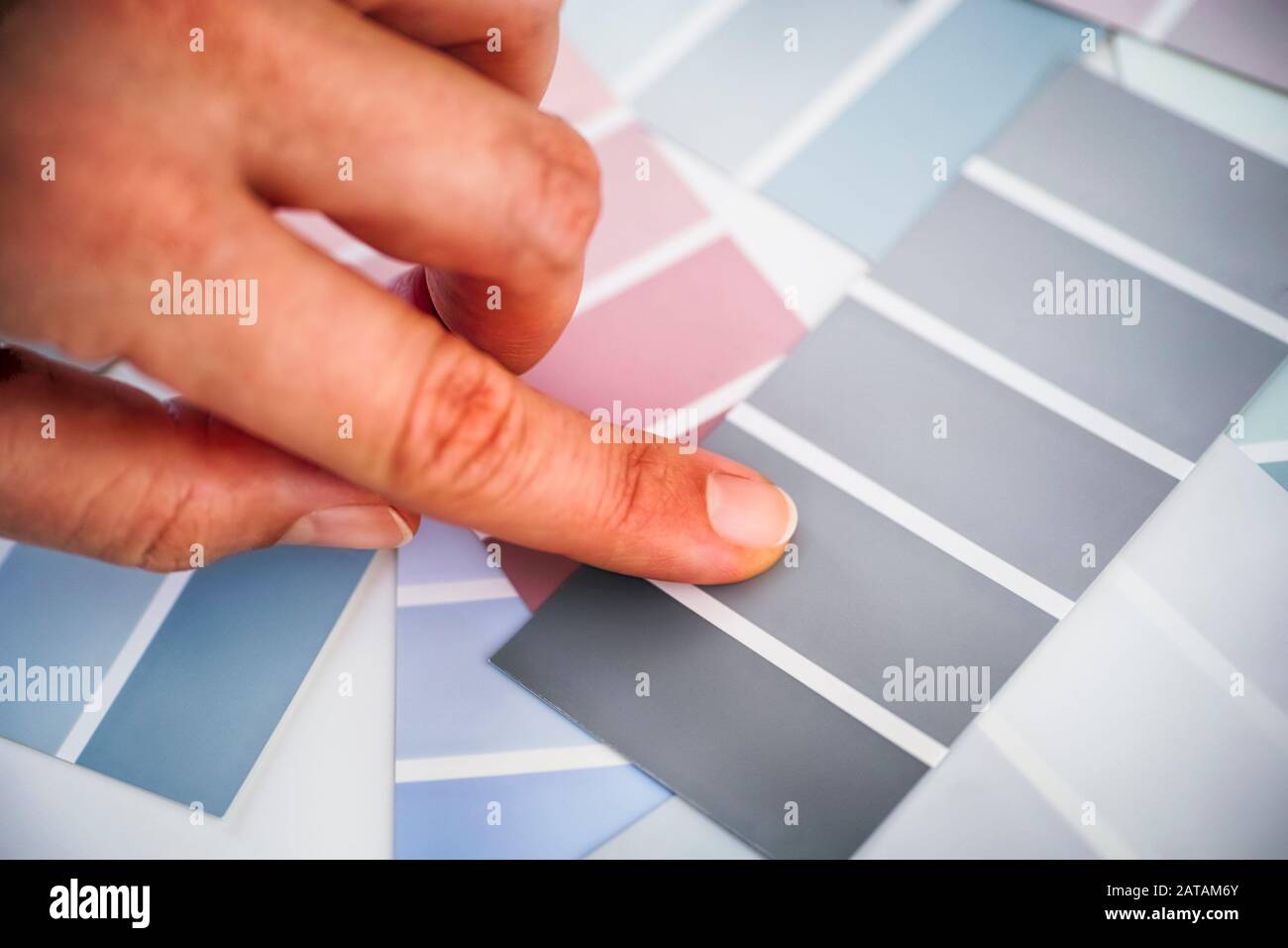 Frau Finger wählt graue Lackfarbe in Probenpaletten. Nahaufnahme. Stockfoto Frau Finger wählt graue Lackfarbe in Probenpaletten. Nahaufnahme. Stockfoto