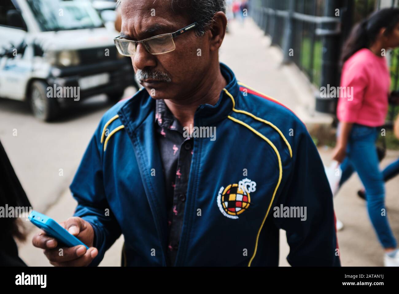 Ein Mann mit Brille, der sein Telefon auf den Straßen Sri Lankas überprüft Stockfoto