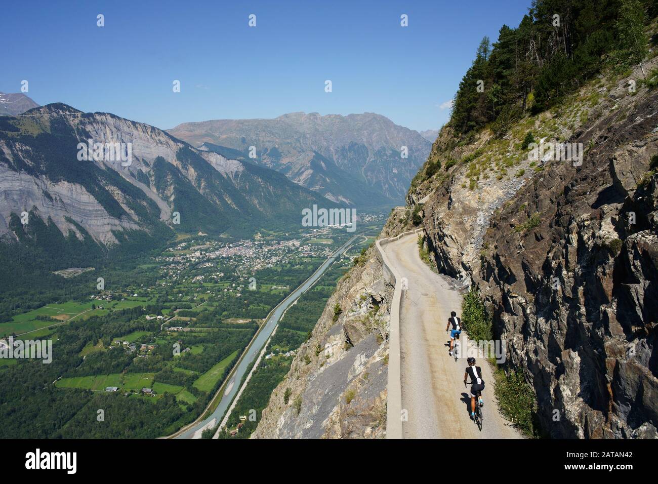LUFTAUFNAHME von einem 6 m hohen Mast. Radfahrer auf einer schmalen Straße über einem steilen Berghang. Auris Road, oberhalb von Le Bourg d'Oisans, Frankreich. Stockfoto