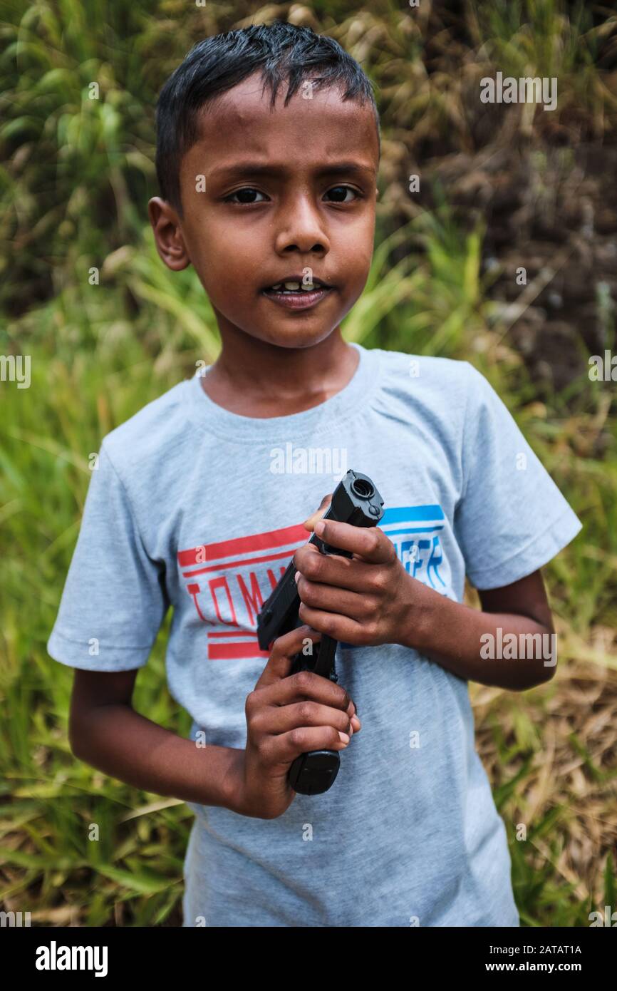 Junger asiatischer Junge, der eine Waffe hält Stockfoto