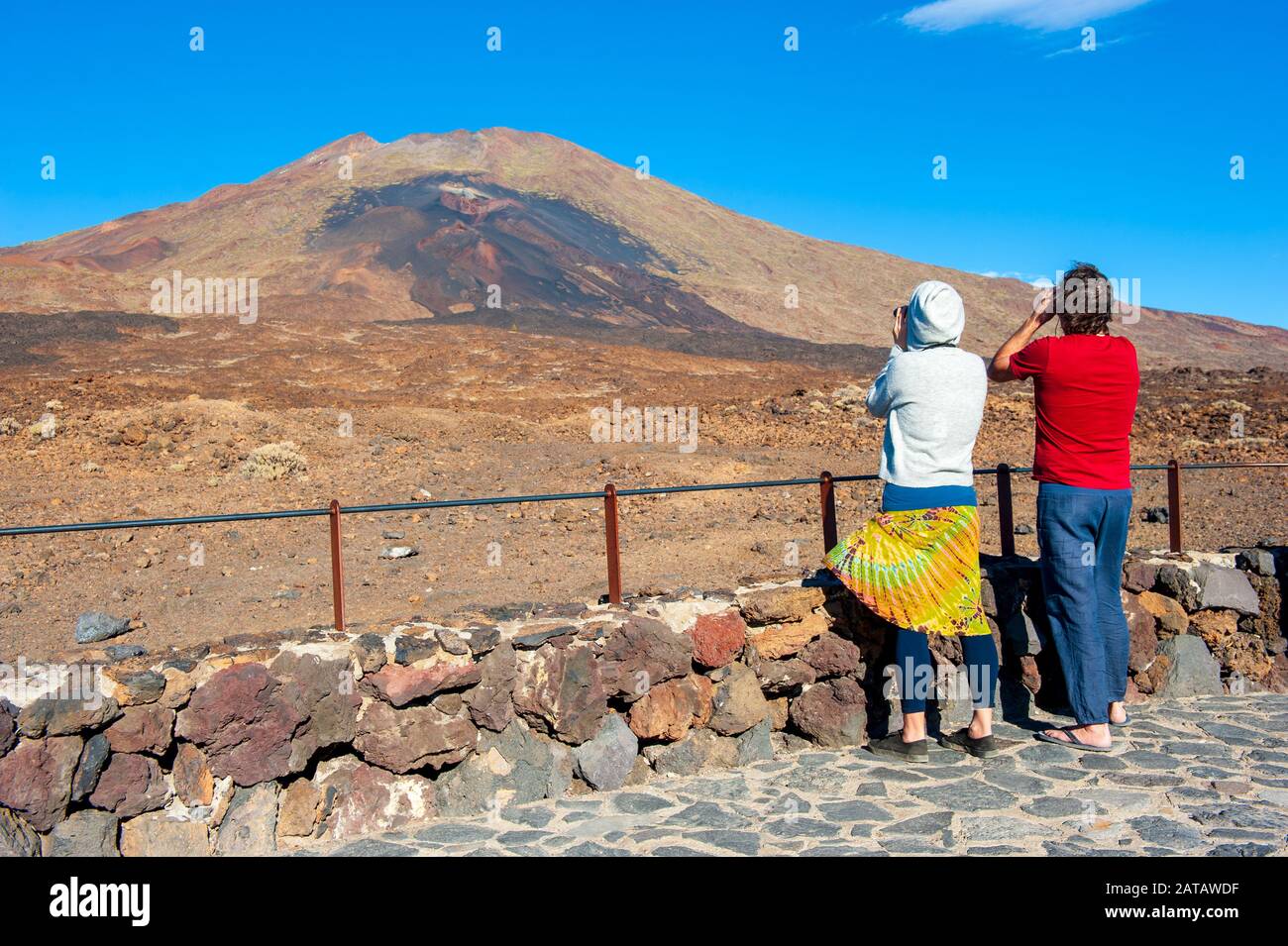 KANARENINSEL TENERA, SPANIEN - 24 DEC, 2019: Touristen mit Ferngläsern beobachten die violette und braune Lava aus den unteren Schlitzen des Vulkans Pico Vie Stockfoto