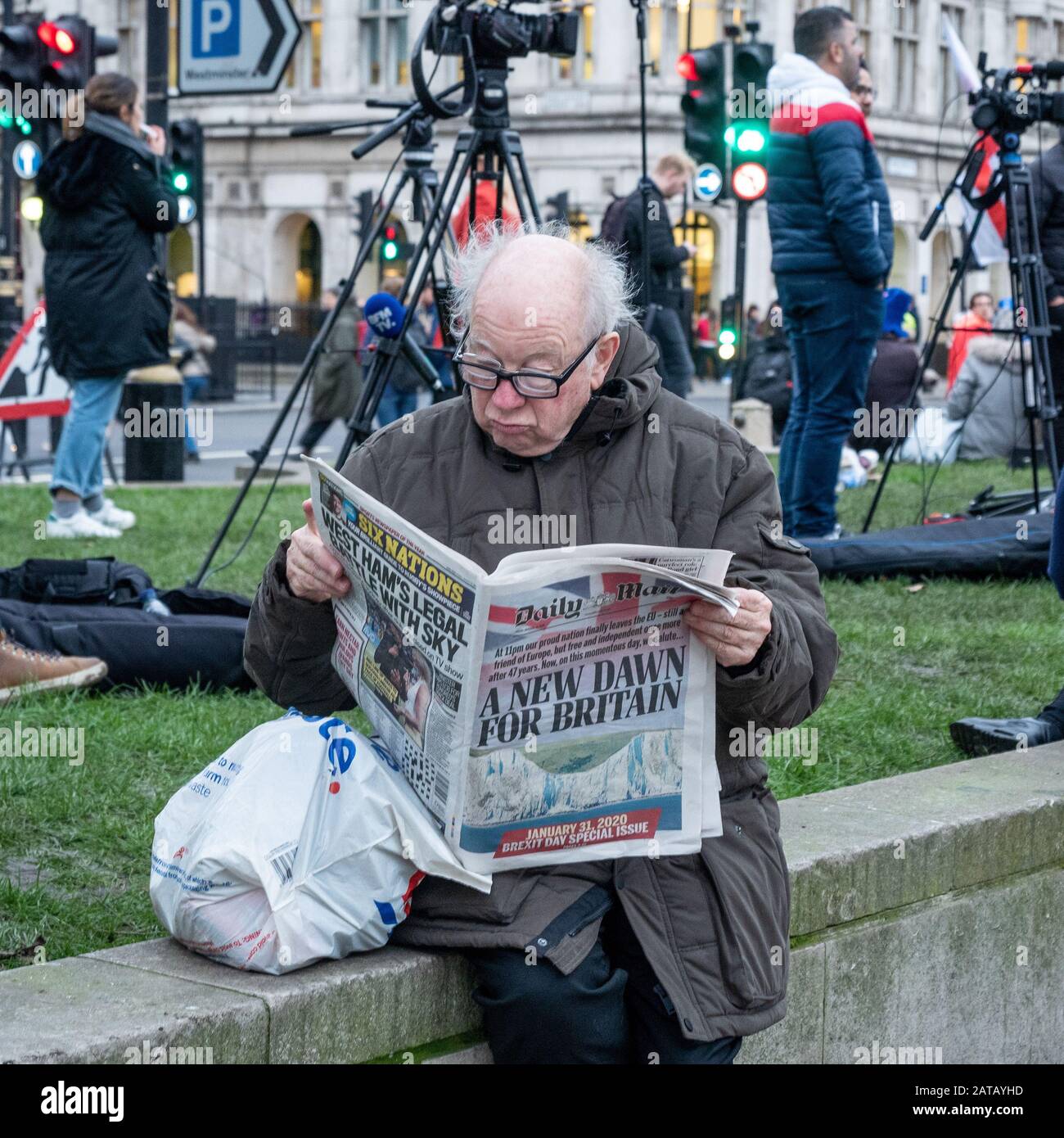 Brexit Day 31. Januar 2020 auf dem Parliament Square, London, England. Ein Mann liest eine Boulevardzeitung und sieht unbeeindruckt aus. Stockfoto
