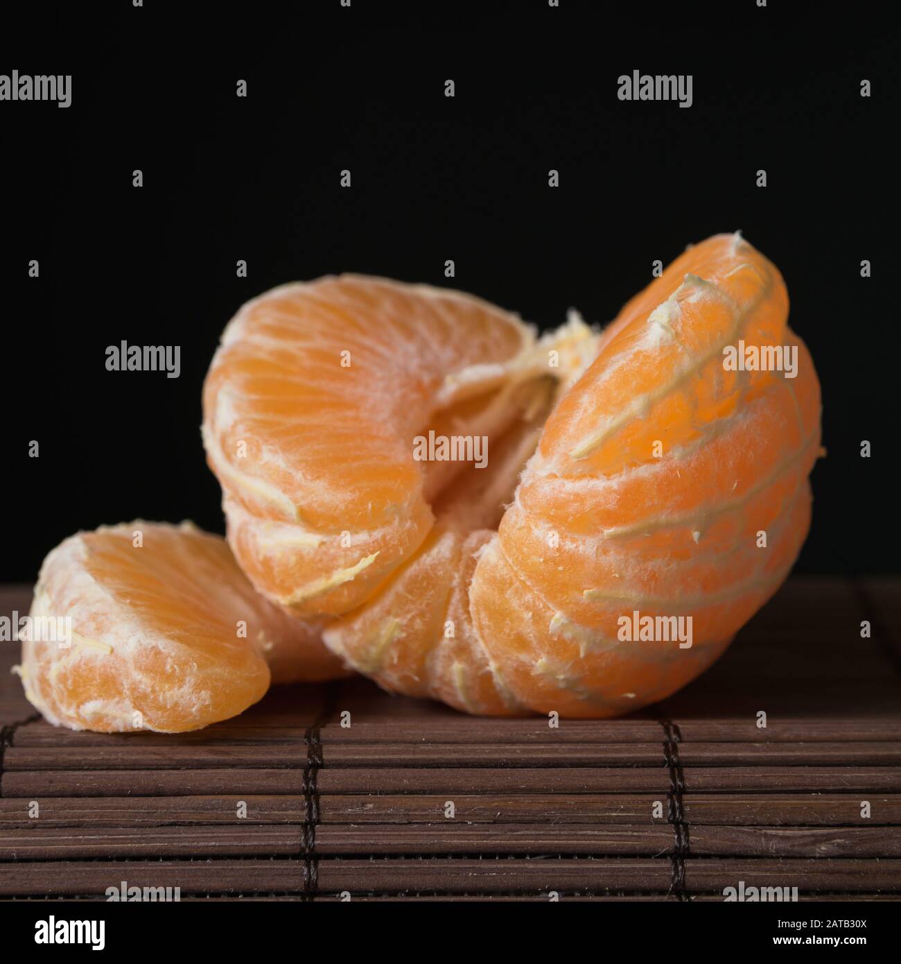 Stillleben, Scheiben von reifen saftigen Mandarinen auf schwarzem Hintergrund Nahaufnahme Stockfoto