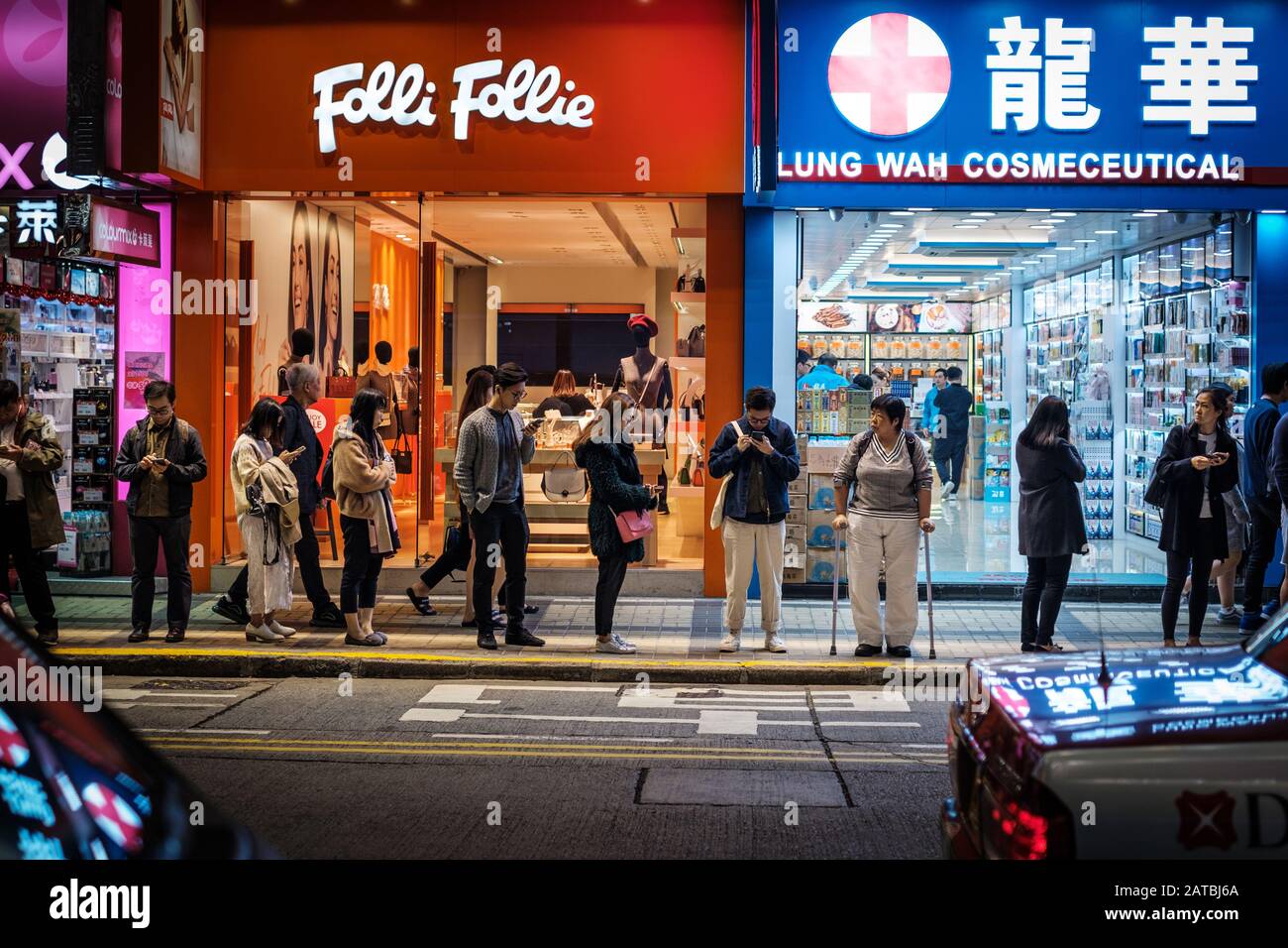 Hongkong - November 2019: Nachts auf der Straße wartende Menschen in Hongkong City, Tsim Sha Tsui Stockfoto