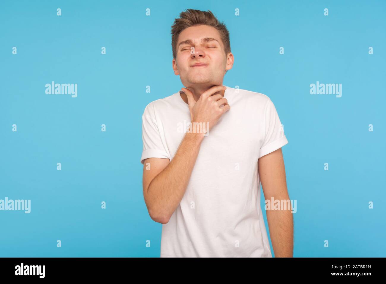 Halsschmerzen, Tonsillitis. Ungesunder grippeseifer Mann in weißem T-Shirt, das kranken Hals hält, schreckliche Kehlschmerzen erleidet, Gesundheit und medizinisches Konzept. In Stockfoto