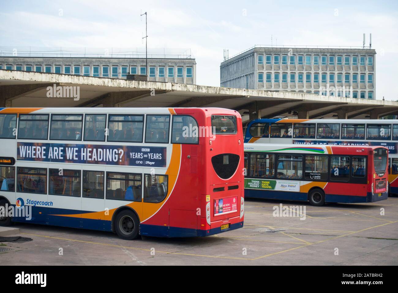 Der moderne Busbahnhof von 1964 in Exeter, Großbritannien, mit modernen Bussen, die unter dem Vordach aus Stahlbeton geparkt sind. Stockfoto