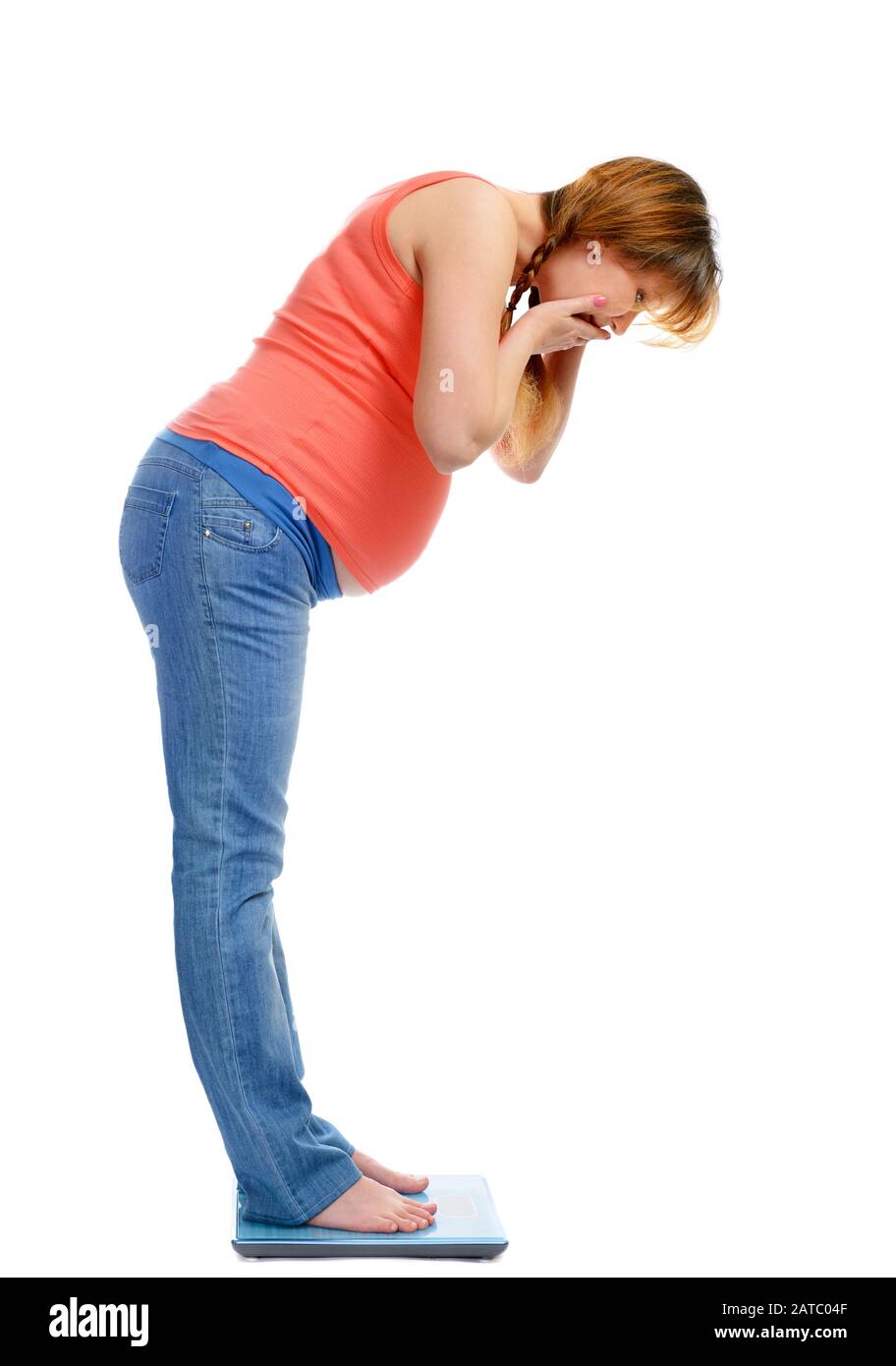 Schwangere Frau auf der Waage überrascht von ihrem Gewicht, isoliert auf Weiß Stockfoto