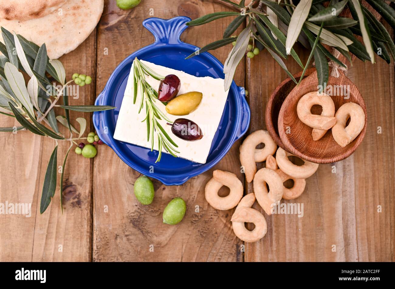 Griechische Fetakäse und Oliven verschiedener Sorten. Traditionelles Brot und Krokodile auf Holzgrund. Kopierbereich. Oben. Stockfoto