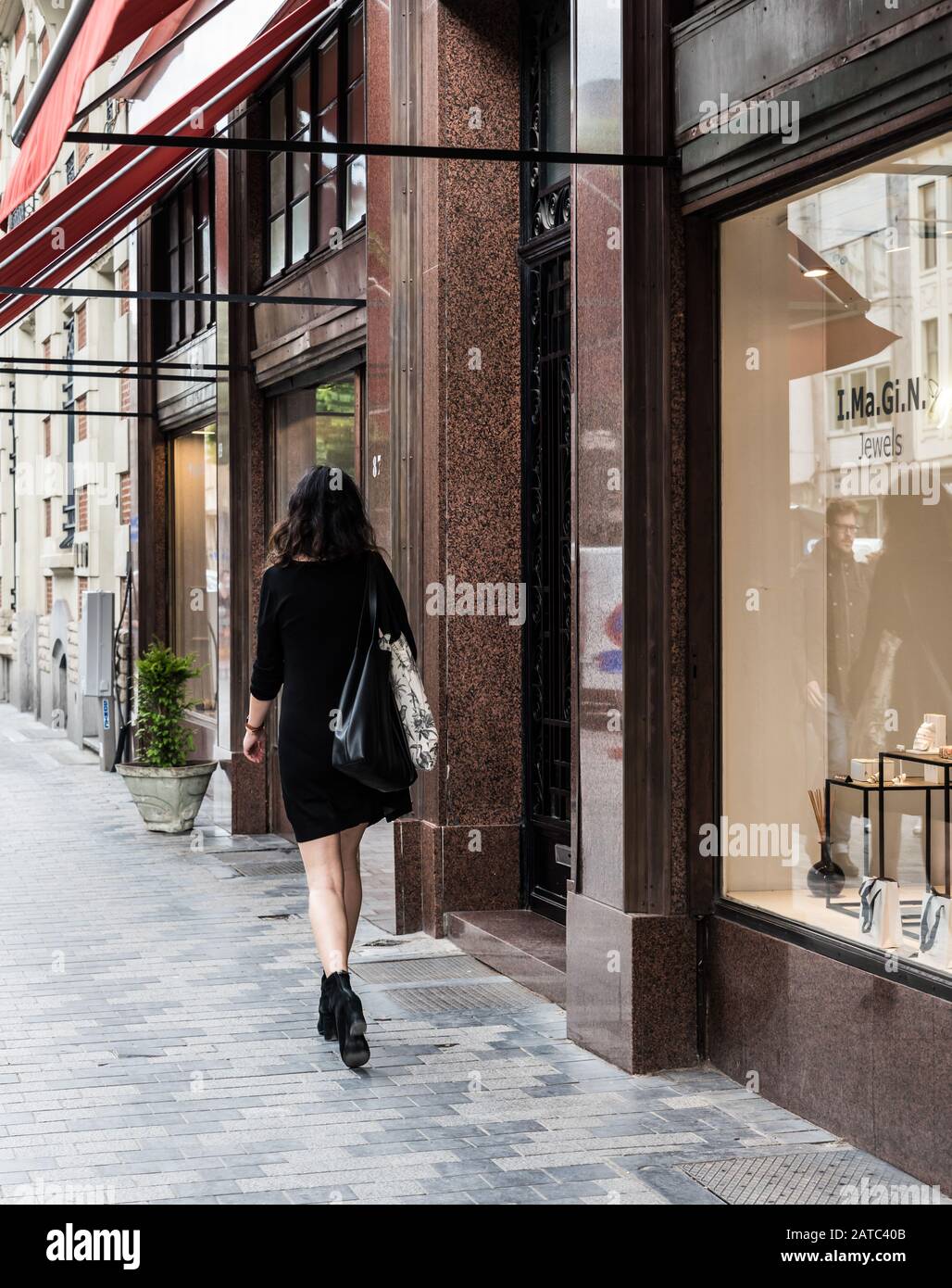 Brüsseler Altstadt / Belgien - 06 07 2019: Stilvoll schöne Frau in schwarzem Kleid, die durch die gehobene Einkaufsstraße Dansaert geht Stockfoto