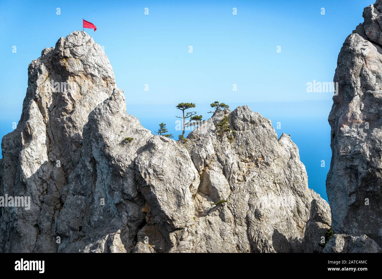 Der Felsen auf dem Berg Ai-Petri mit roter Flagge und Bäumen über dem Schwarzen Meer auf der Krim, Russland. Ai-Petri ist eines der höchsten Berge der Krim und Touristen Stockfoto