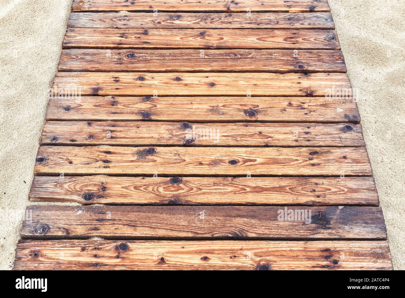 Holzweg an einem sandigen Strand im Sommer. Natürliche Holzbohlen Hintergrund. Der Touristenweg mit einer alten Deckeldecke zum Meer in der Nähe. Draufsicht über den Fußweg Stockfoto