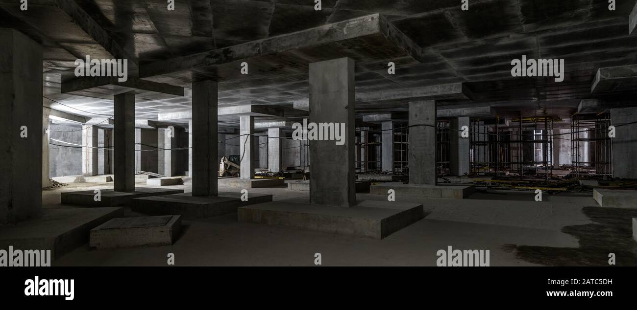 Betonkonstruktion des Untergeschosses eines großen Gebäudes. Panorama im Inneren der modernen Baustelle im Dunkeln. Zeitgenössische Struktur im Bau w Stockfoto