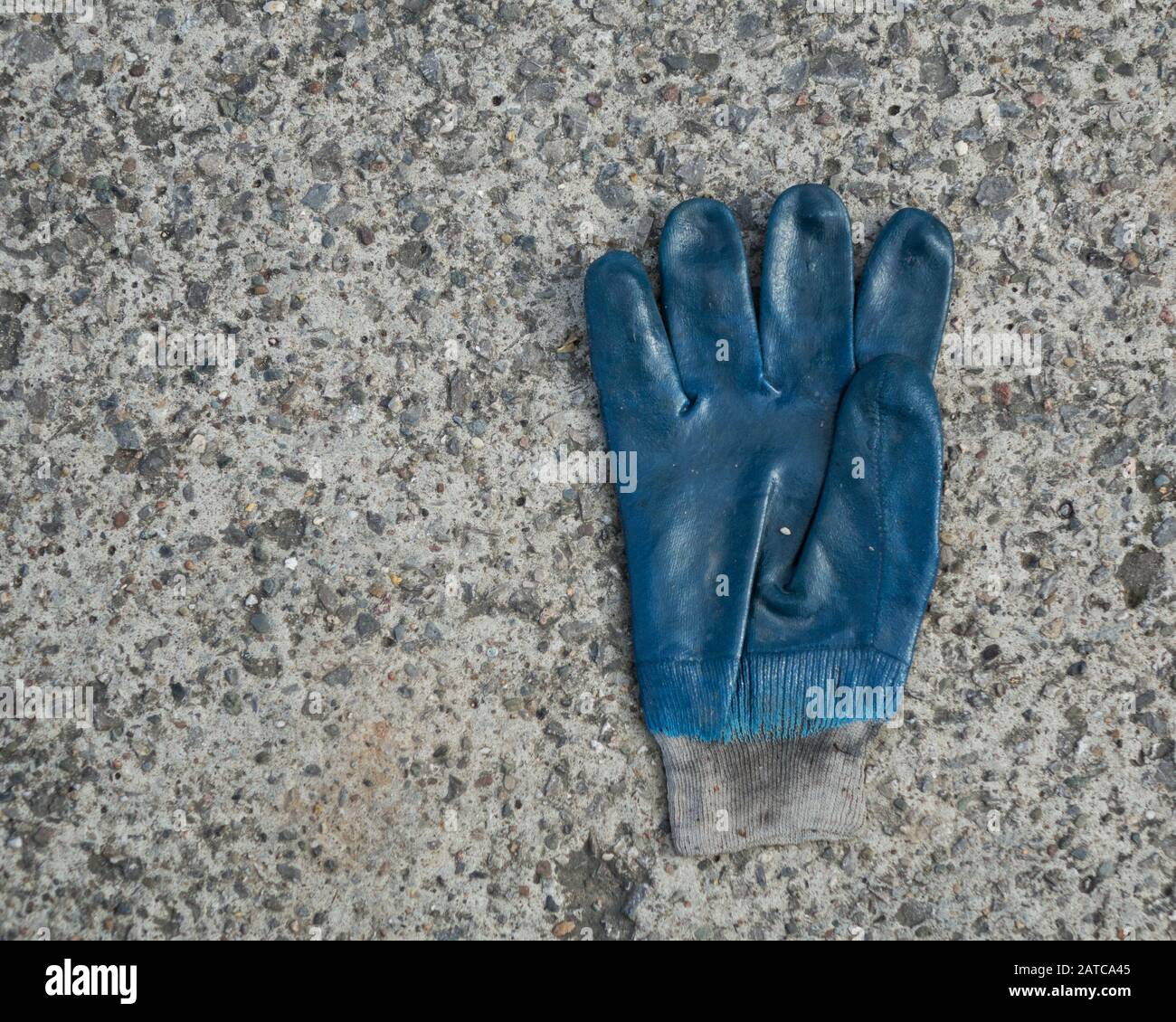 Rechtshändiger blauer Gummischutzhandschuh auf Betonboden Stockfoto