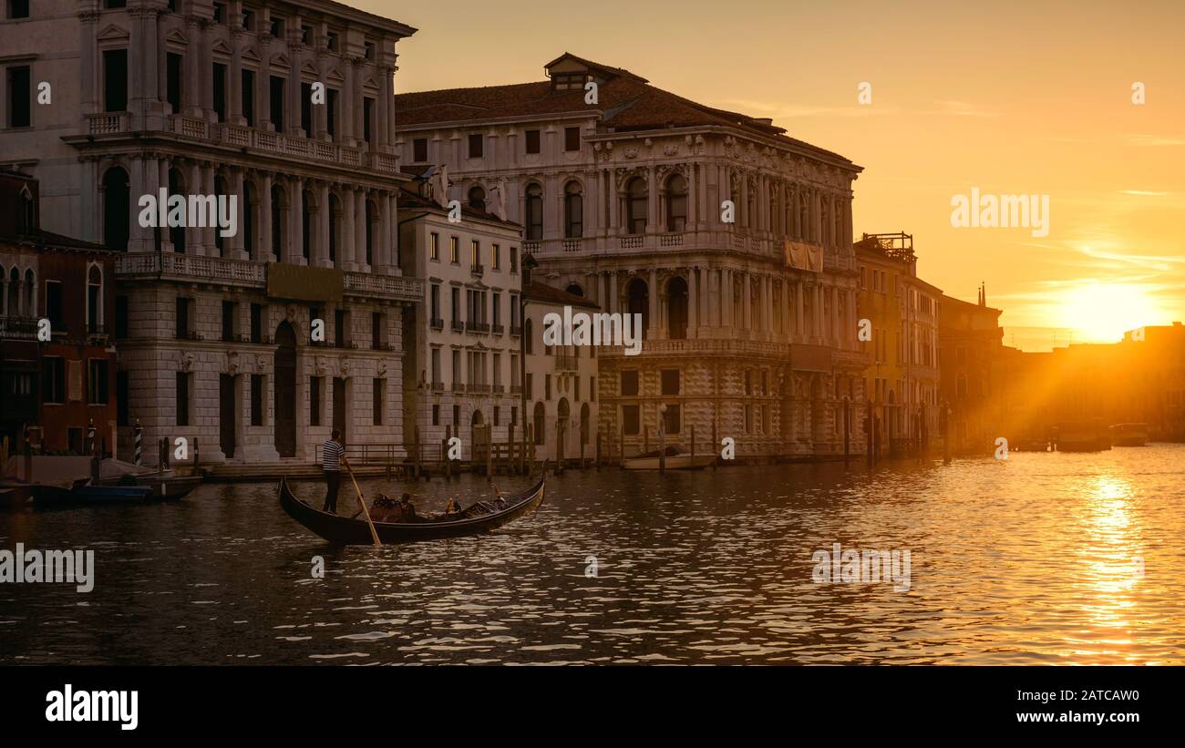 Venedig bei Sonnenuntergang, Italien. Gondel mit Touristen segelt nachts auf dem Canal Grande. Panorama der Stadt Venedig im Abendlicht. Landschaft der sonnigen Straße im Stockfoto