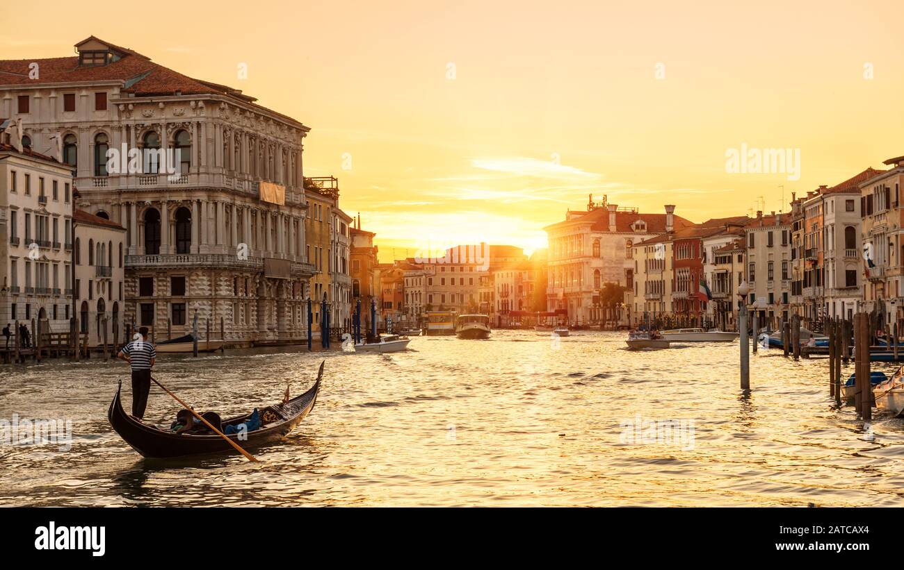 Venedig bei Sonnenuntergang, Italien. Gondel mit Touristen segelt nachts auf dem Canal Grande. Blick auf die Stadt Venedig bei Sonneneinstrahlung am Abend. Landschaft der sonnigen Straße in Stockfoto
