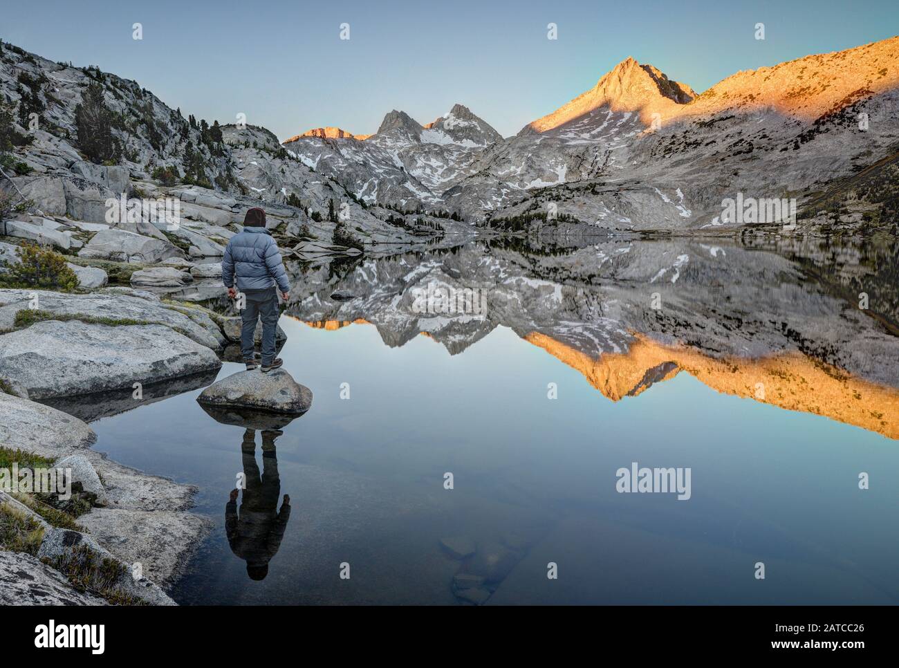 Mann, der auf einem Felsen steht und auf Mount Hooper Reflection in Rose Lake, Sierra National Forest, Kalifornien, USA blickt Stockfoto